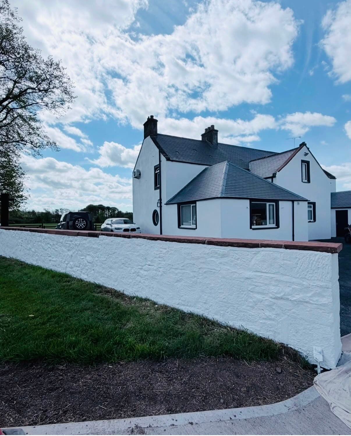 Exterior repaint of a traditional sandstone house with white window frames and a charcoal door